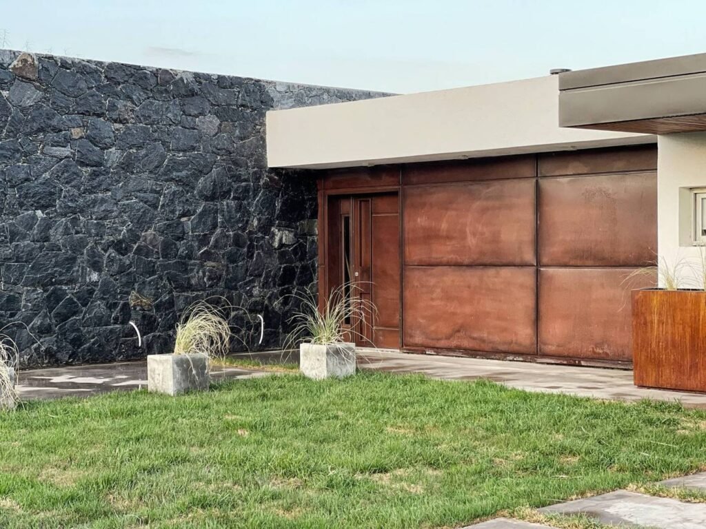 Casa E11 en Estación del Carmen, Malagueño: ingreso con piedra y óxido